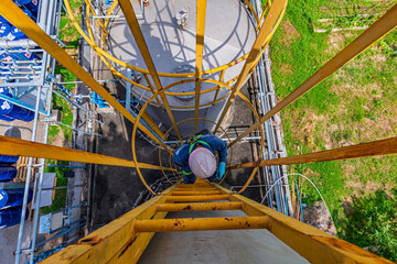 Male worker climbs up the ladder inspection stainless tank work at height