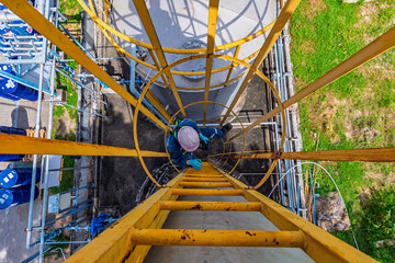 Male worker climbs up the ladder inspection stainless tank work at height
