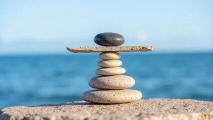 Balanced stones create serene and calming scene by water, symbolizing harmony and tranquility