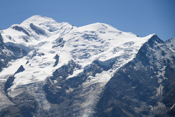 Panoramic view of Mont Blanc covered in snow under a clear blue sky. Captured during the Tour du Mont Blanc hike. Iconic Alpine mountain landscape.
