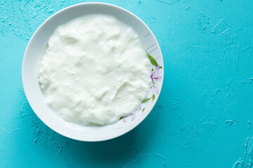 natural yoghurt in white bowl on blue background
