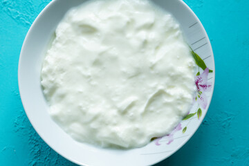 natural yoghurt in white bowl on blue background