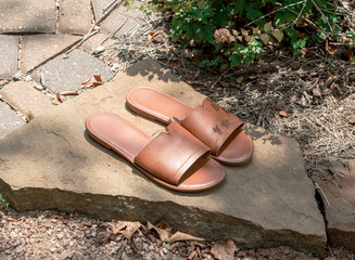 slide sandals on a flat rock next to a garden
