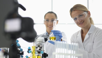 Two scientists conduct experiments in a bright lab filled with advanced equipment and colorful test...