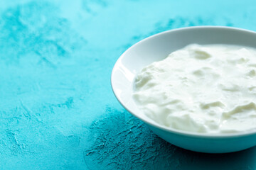 natural yoghurt in white bowl on blue background