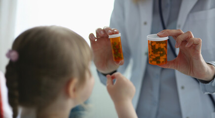 Engaging child at a pediatric consultation with colorful medication bottles in hand during a bright afternoon