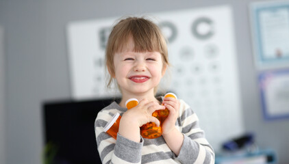Smiling child holds toy while standing in bright room during afternoon playtime