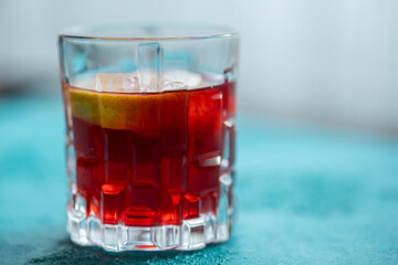 Lemon slices in red cocktail in crystal glass on blue background