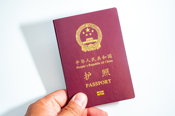 A close-up view of the cover of a dark red passport from the People's Republic of China, featuring the national emblem and "护照 PASSPORT" in golden text.