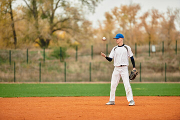 Talented teenage boy practices baseball skills on the field during autumn