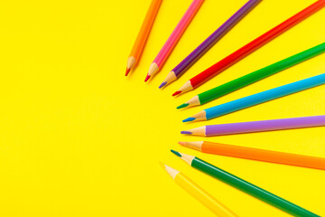 Colored pencils on a bright colored background. Equipment for coloring. Stationery for...