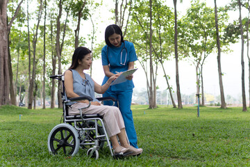 A friendly nurse assists an elderly woman in a wheelchair, providing care, support, and...