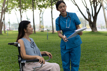 A friendly nurse assists an elderly woman in a wheelchair, providing care, support, and...