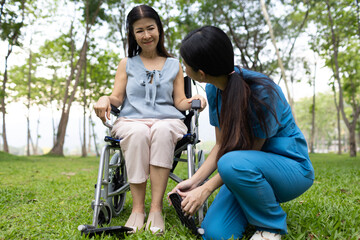 A friendly nurse assists an elderly woman in a wheelchair, providing care, support, and...