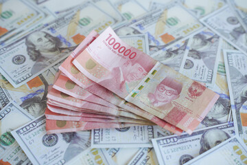 background of piles of US dollar banknotes overlapping Indonesian rupiah banknotes. illustration of inflation of the US dollar currency against the Indonesian rupiah currency