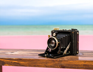 Vintage Black Camera on Wooden Table by Pink Wall at Beach