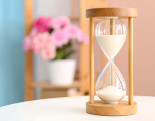 Wooden Hourglass with Sand on White Table, Pink Flowers in Background