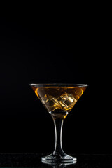 Classic cocktail glass filled with whiskey and ice cubes, photographed in close-up, against a dark black background for a premium beverage concept
