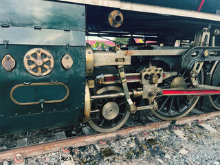 Close-up view of vintage steam locomotive wheels and mechanical parts on railway track. Historical...