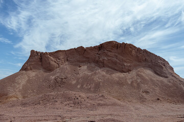 Eroded desert hill under blue sky with wispy clouds in arid landscape. concept of natural dry...