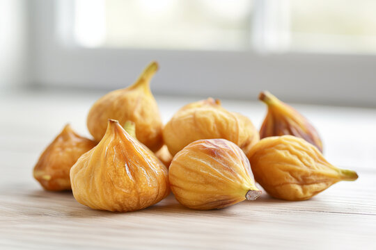 Close-up of dried figs on a light wooden table in bright high-key natural light, created with AI, showing wrinkled texture and natural tones in a clean kitchen setting. - Powered by Adobe