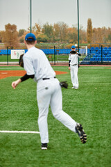 Obraz premium Two teenage boys enjoy baseball practice on a green field during a cloudy day
