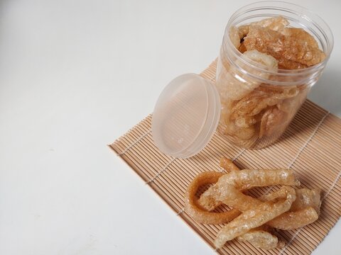 Kerupuk kulit sapi or rambak or beef skin crackers in plastic jar isolated on white background. Crackers with a savory and crispy taste