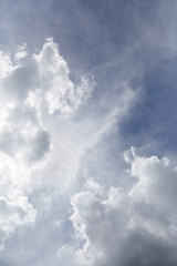 Expansive blue sky with fluffy white clouds, showcasing a serene atmosphere and soft sunlight filtering through, creating a tranquil and peaceful outdoor scene