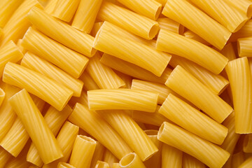 Close-up view of uncooked tortiglioni pasta pieces arranged in a random pattern, showcasing their...