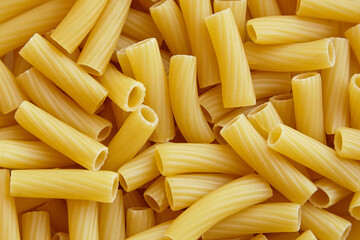 Close-up view of uncooked tortiglioni pasta arranged in a random pattern, showcasing the smooth...