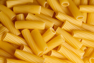 Close-up view of uncooked tortiglioni pasta pieces arranged in a random pattern, showcasing their cylindrical shape and textured surface, ideal for culinary presentations and recipes