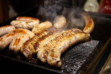 Grilled sausages sizzling on a hot grill, showcasing a variety of textures and colors, with steam rising, creating an appetizing and inviting culinary scene