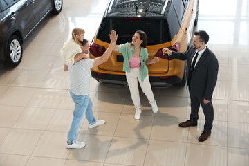 Salesman giving car key to happy family in salon