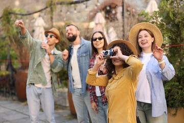 Guide with microphone and group of tourists on city street during excursion, selective focus