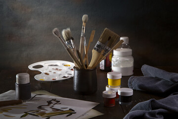 Still life with brushes and paints on a dark background