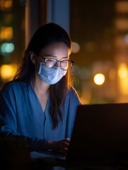 person wearing a medical face mask while working remotely on a laptop, in a home office setting. The scene conveys adaptability, safety, and the integration of masks into daily life. person, 