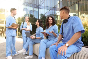 Fototapeta premium Group of medical students in uniforms studying together near building outdoors
