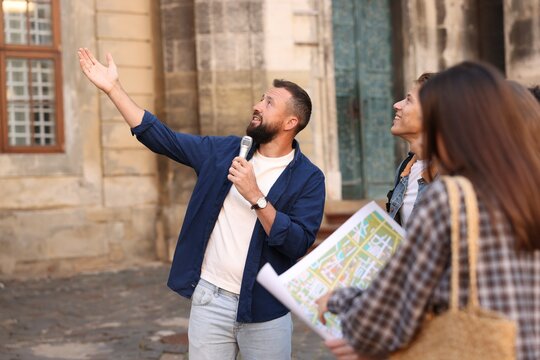 Guide with microphone and tourists on city street during excursion