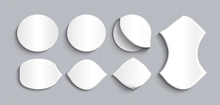 Set of various blank white shapes, like stickers or labels, with different geometric forms, including circles, ovals, and curved shapes, on a light gray background