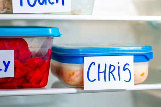 Office lunch containers with handwritten name labels in shared fridge. Healthy food preparation for work office study.