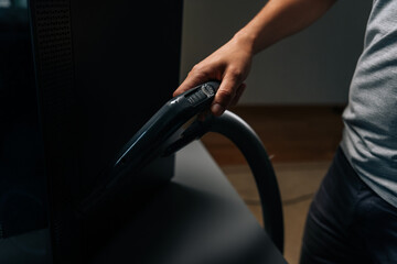 Technician male using vacuum cleaner to remove dust and debris from computer in repair shop,...