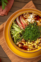 Okroshka soup with kvass vegetables and herbs in yellow bowl