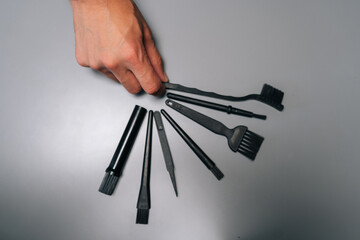 Top view of technician holding set of specialized cleaning tools, including brushes, tweezers,...