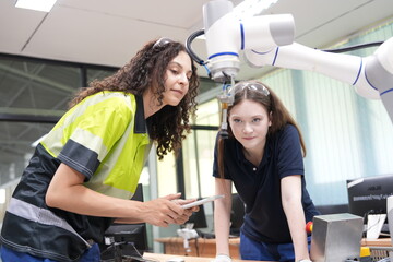 Two female engineers learn programming software for automated manufacturing technology and for use...