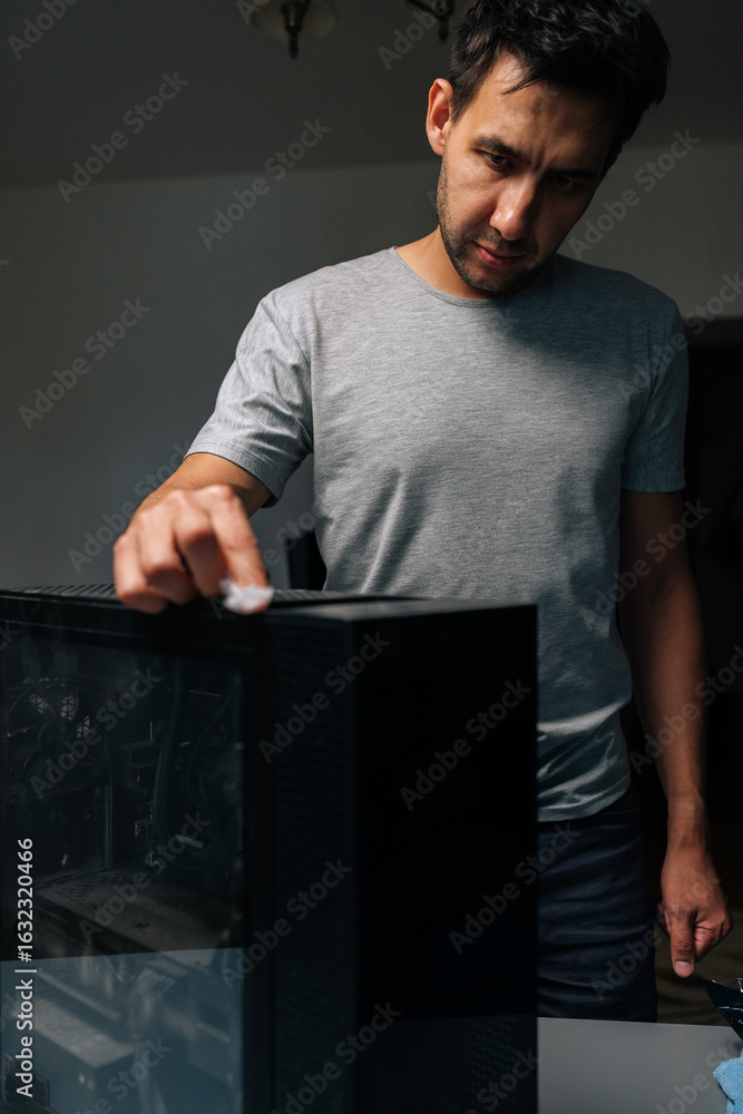 Poster vertical portrait of technician male wiping computer case, removing dust and grime for maintaining e