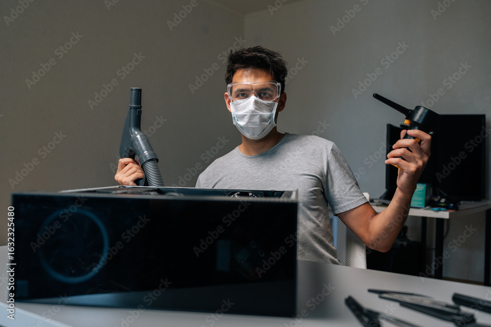 Poster portrait of skilled computer technician wearing protective gear, cleaning computer case with vacuum 