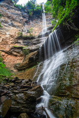 Fototapeta premium A stunning multi-tiered waterfall cascading down rocky cliffs surrounded by lush greenery.