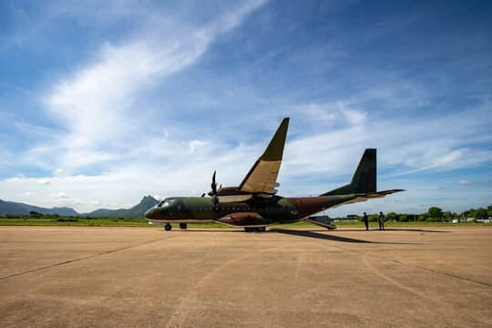 Aircraft Ground Prep, Soldiers walking with gear near a military transport plane on a runway, preparing for deployment.