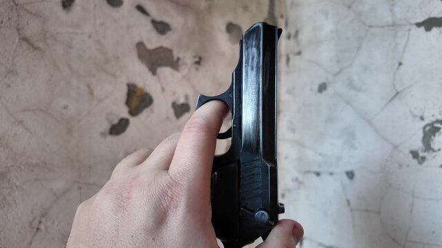 Black automatic pistol in hand. Man shoots from pistol. Concept weapon. Old pistol.