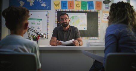 Male Teacher Giving School Test Results of Elementary School Child to His Mother. Teacher...